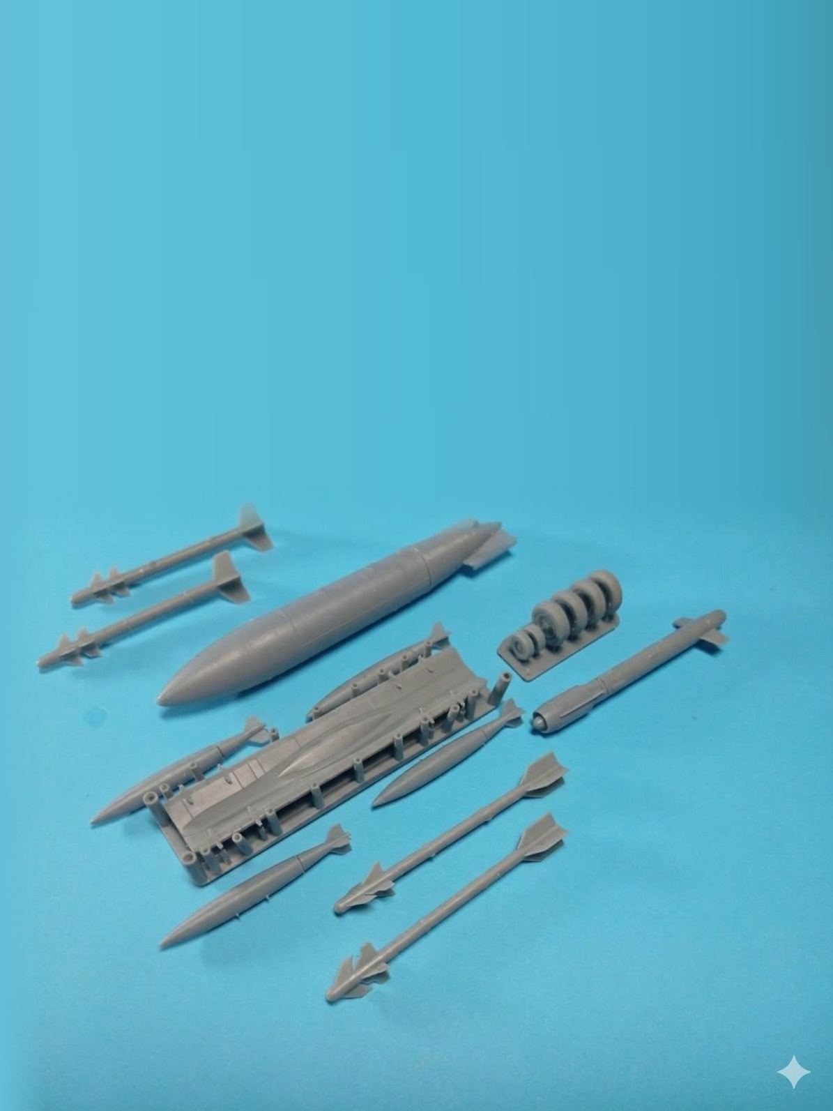 Grey resin aircraft accessories and weapons on a blue background